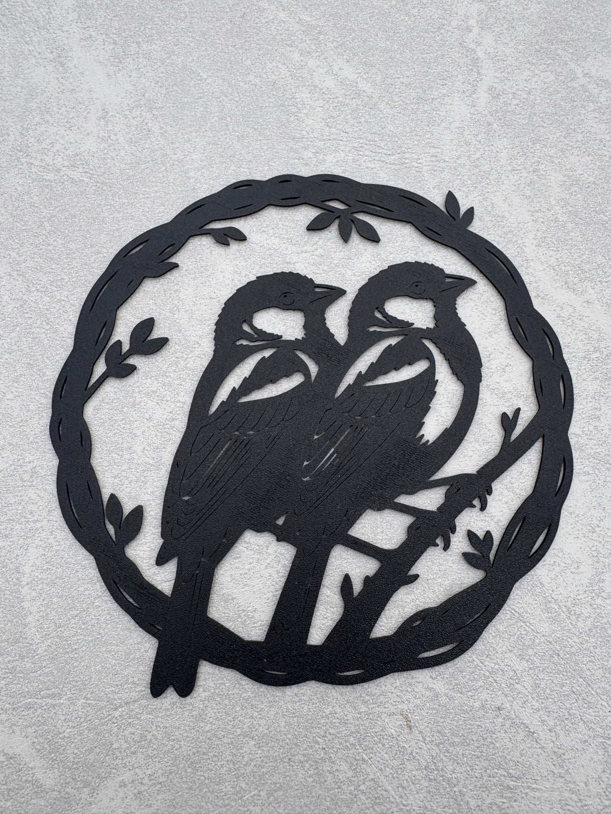Two birds sitting on branch inside olive branch circle